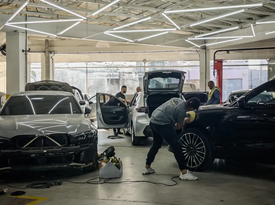 Salão da oficina, com carros em serviço e a equipe trabalhando