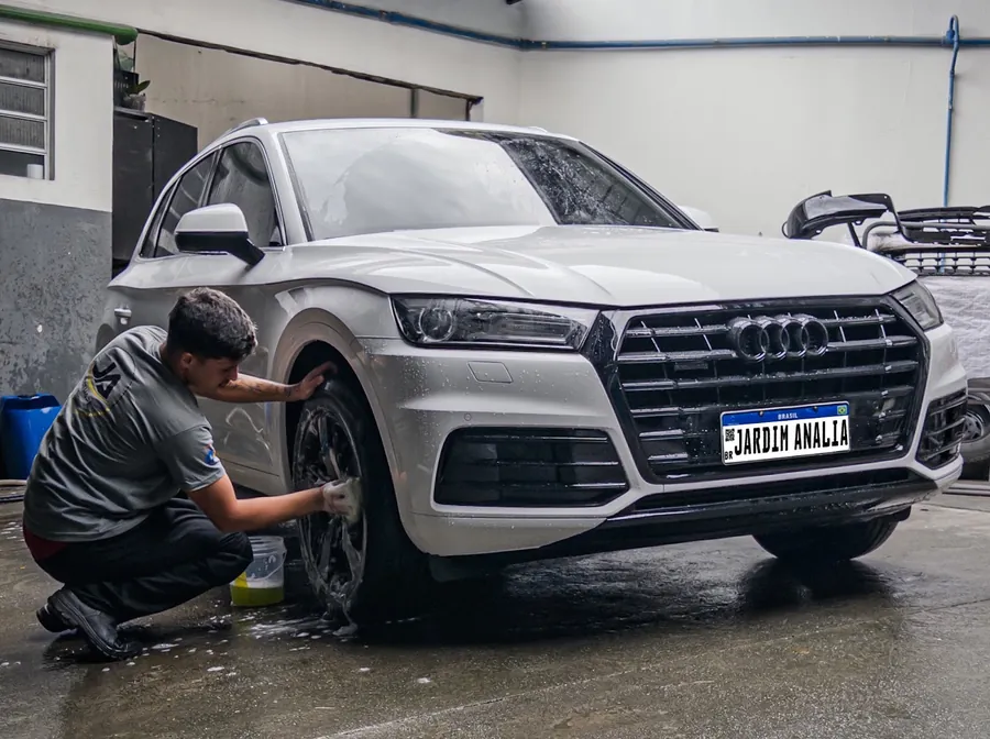 Profissional uniformizado lavando a roda de um carro